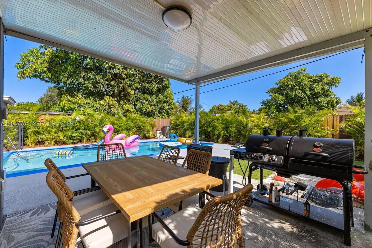 A covered patio features a dining set and a grill overlooking a backyard swimming pool — 1240 NE 159th St, North Miami Beach FL 33162, NORTH MIAMI BEACH, FL