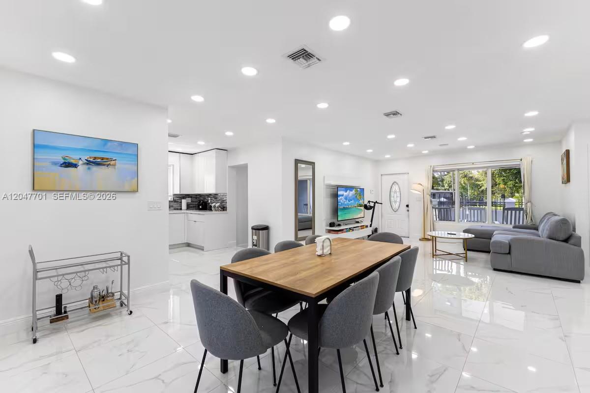 A bright, open-concept living and dining area features white tile floors and recessed lighting — 1240 NE 159th St, North Miami Beach FL 33162, NORTH MIAMI BEACH, FL
