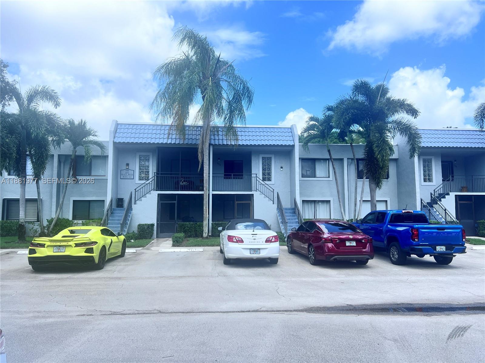 A two-story apartment building with a blue tiled roof and four parked cars in front — 16531 Blatt Blvd # 103, Weston FL 33326, WESTON, FL
