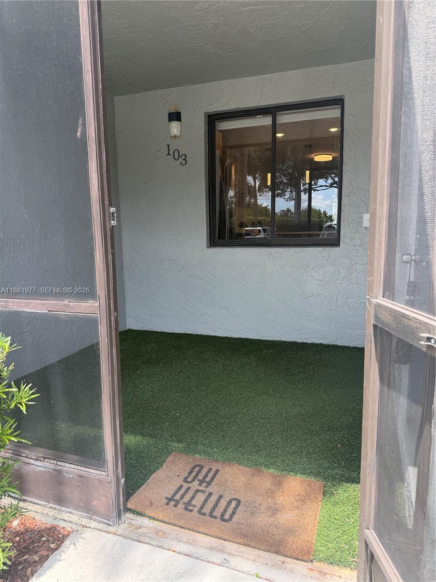 A covered patio with artificial turf flooring features a window and a welcome mat — 16531 Blatt Blvd # 103, Weston FL 33326, WESTON, FL