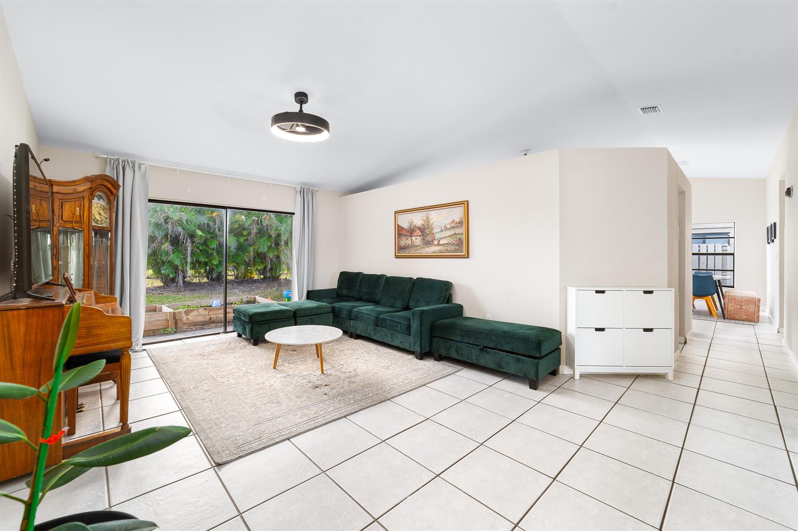 A living room features a green sectional sofa, a white coffee table, and tile flooring — 1060 Cedar Creek Way, Davie FL 33325, DAVIE, FL