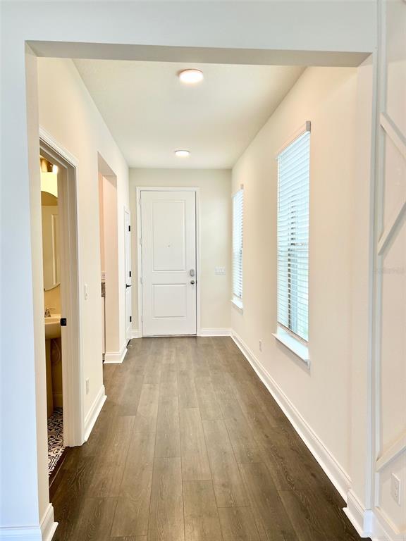A hallway features wood-look flooring, a white front door, and a bathroom entrance — 9359 JUNIPER MOSS CIRCLE, ORLANDO, FL