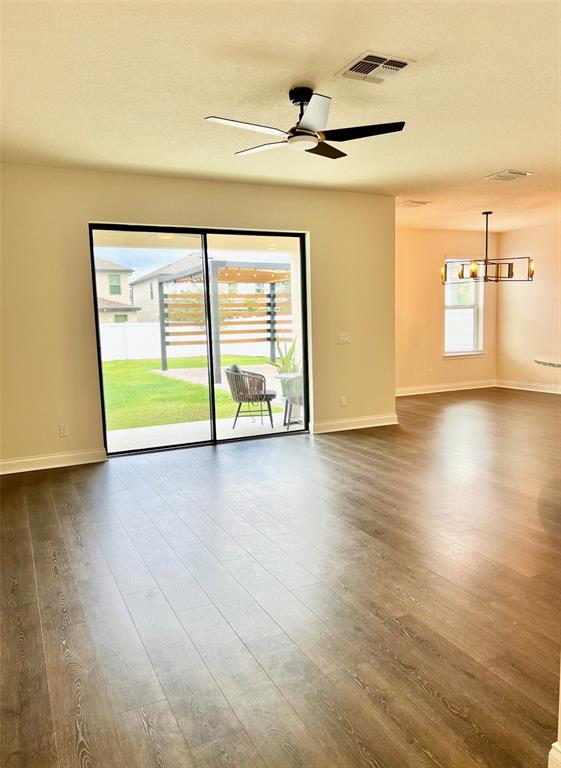 A bright living area features wood-look flooring, a ceiling fan, and sliding doors to a patio — 9359 JUNIPER MOSS CIRCLE, ORLANDO, FL