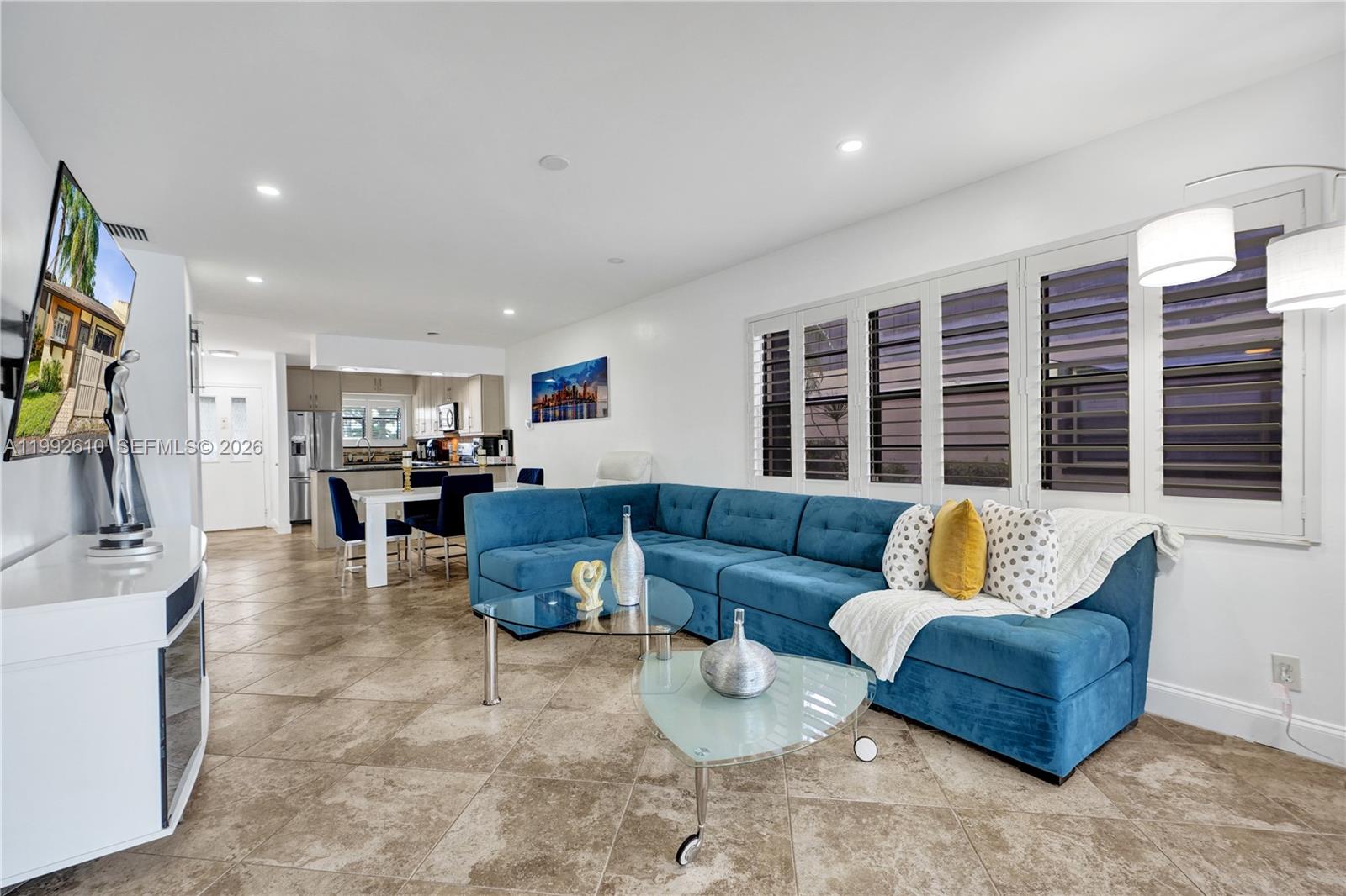 A living room features a blue sectional sofa, glass coffee tables, and tile flooring — 707 Banks Rd, Margate FL 33063, MARGATE, FL