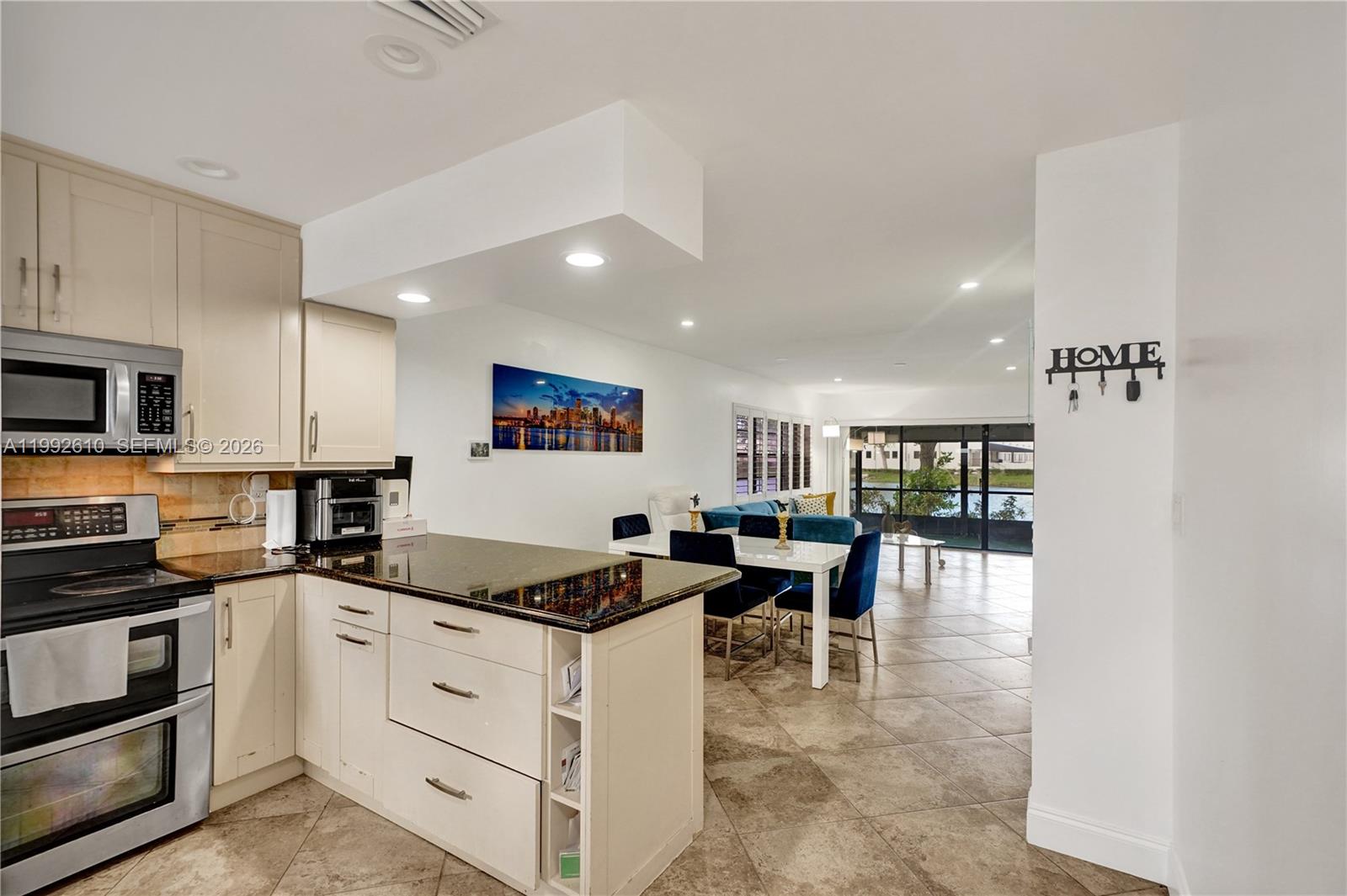 A kitchen with granite countertops opens into a dining area and a living room — 707 Banks Rd, Margate FL 33063, MARGATE, FL