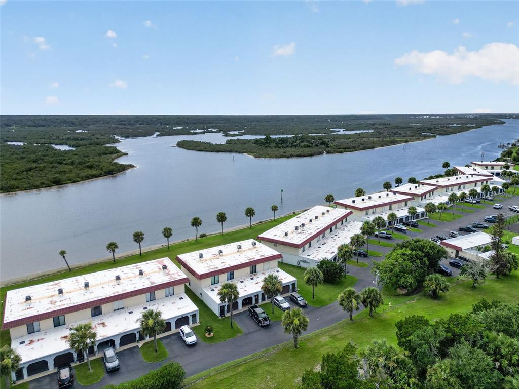 An aerial view shows multi-unit townhomes with flat roofs and garages near a waterfront — 24 S OCEAN PALM DRIVE UNIT 24, FLAGLER BEACH, FL