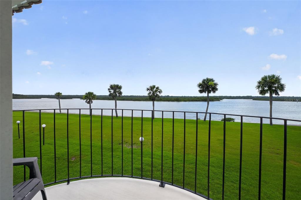 A balcony with a black metal railing overlooks a grassy lawn and a body of water — 24 S OCEAN PALM DRIVE UNIT 24, FLAGLER BEACH, FL