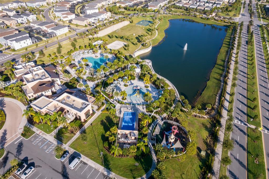 Aerial view of a community clubhouse featuring swimming pools, a playground, and a large pond — 2166 FLEMING MIST PLACE, KISSIMMEE, FL