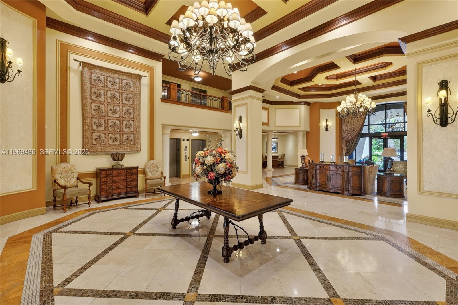 A grand lobby features a large wooden table, chandeliers, and decorative tile flooring — 888 S Douglas Rd # 1204, Coral Gables FL 33134, CORAL GABLES, FL