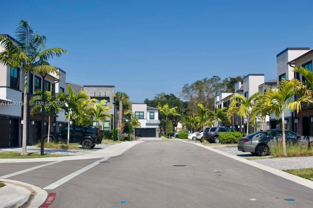 A street view of modern townhomes with palm trees and parked cars under a blue sky — 8352 NW 7th Pl, Plantation FL 33324, PLANTATION, FL