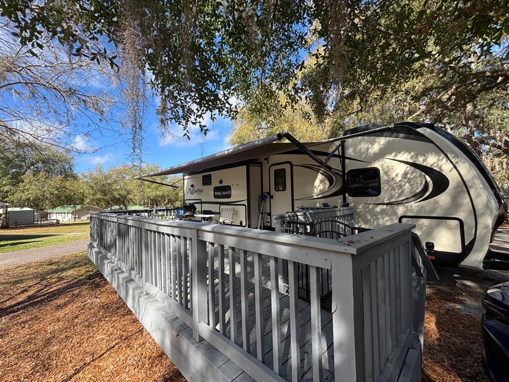 A travel trailer with an extended awning sits next to a wooden deck — 25163 NE 140TH LOOP NE UNIT 17, FORT MC COY, FL