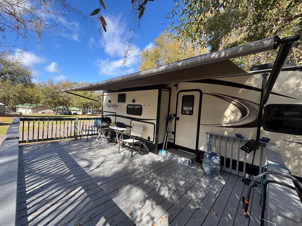 A travel trailer with an extended awning sits on a wooden deck outdoors — 25163 NE 140TH LOOP NE UNIT 17, FORT MC COY, FL