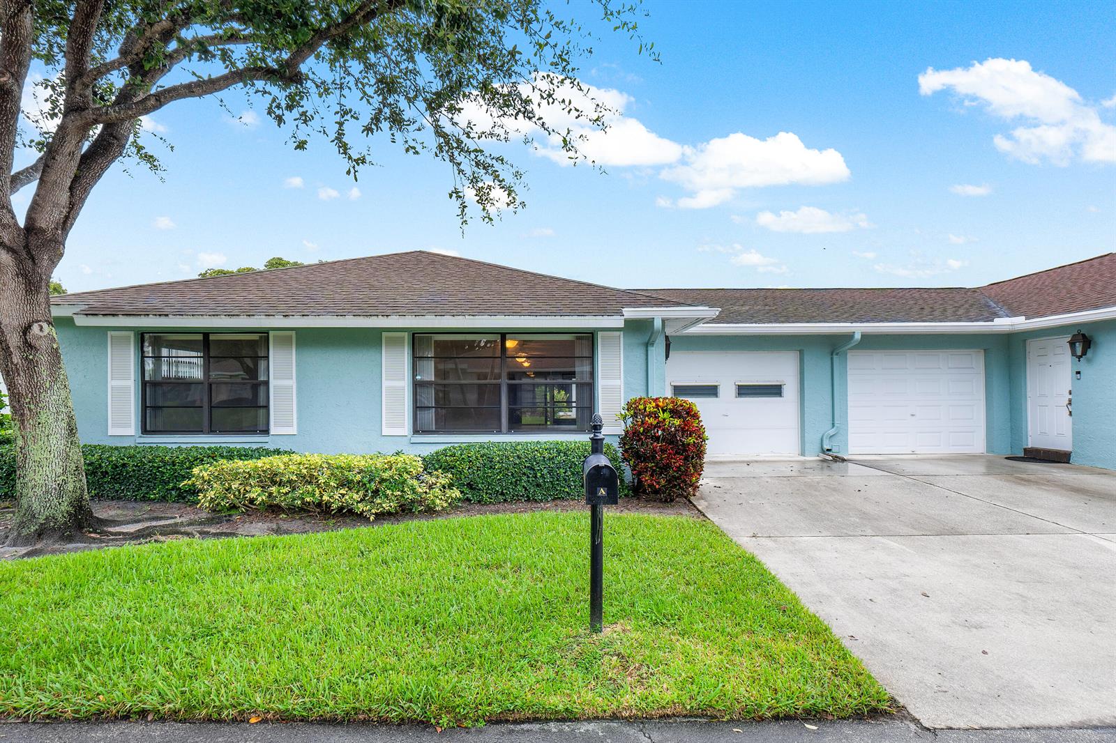 A light blue single-story house features a two-car garage, white shutters, and a front lawn — 4360 Eucalyptus Tree Court # A, Boynton Beach FL 33436, BOYNTON BEACH, FL