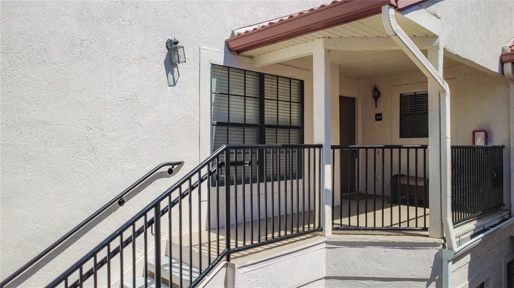 An exterior view of an apartment entrance with a staircase, black railings, and a porch — 535 VIA FONTANA DRIVE UNIT 202, ALTAMONTE SPRINGS, FL
