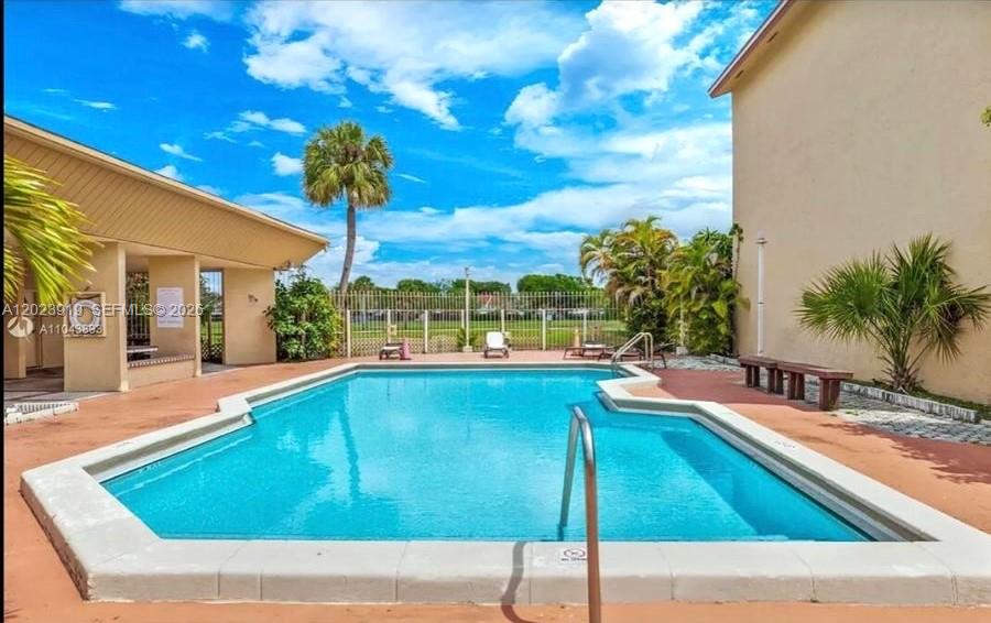 An outdoor swimming pool is situated between two buildings on a sunny day — MIAMI, FL