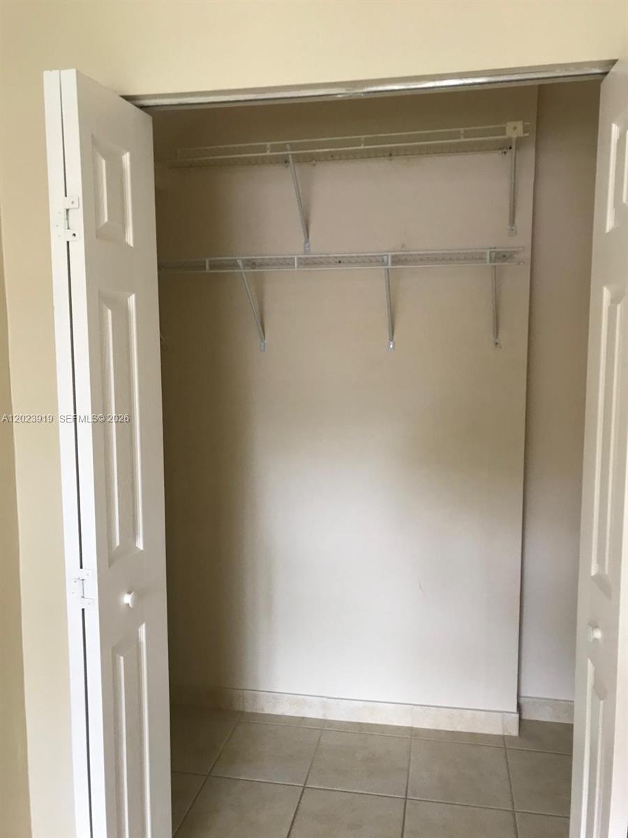 A closet with white bifold doors, wire shelving, and light-colored tile flooring — MIAMI, FL