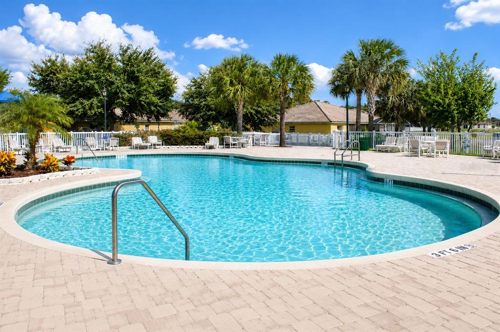A swimming pool with a paved deck, palm trees, and lounge chairs in the background — 212 OCEAN BLUFF DRIVE, POINCIANA, FL