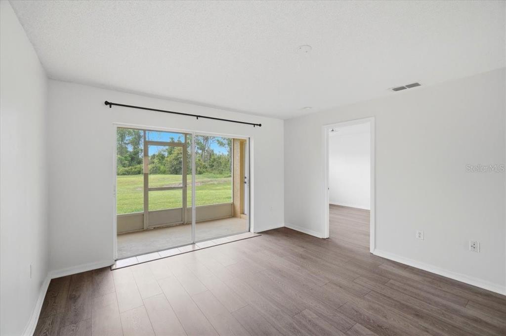 A room with wood-look flooring, white walls, and a sliding glass door leading to a patio — 212 OCEAN BLUFF DRIVE, POINCIANA, FL