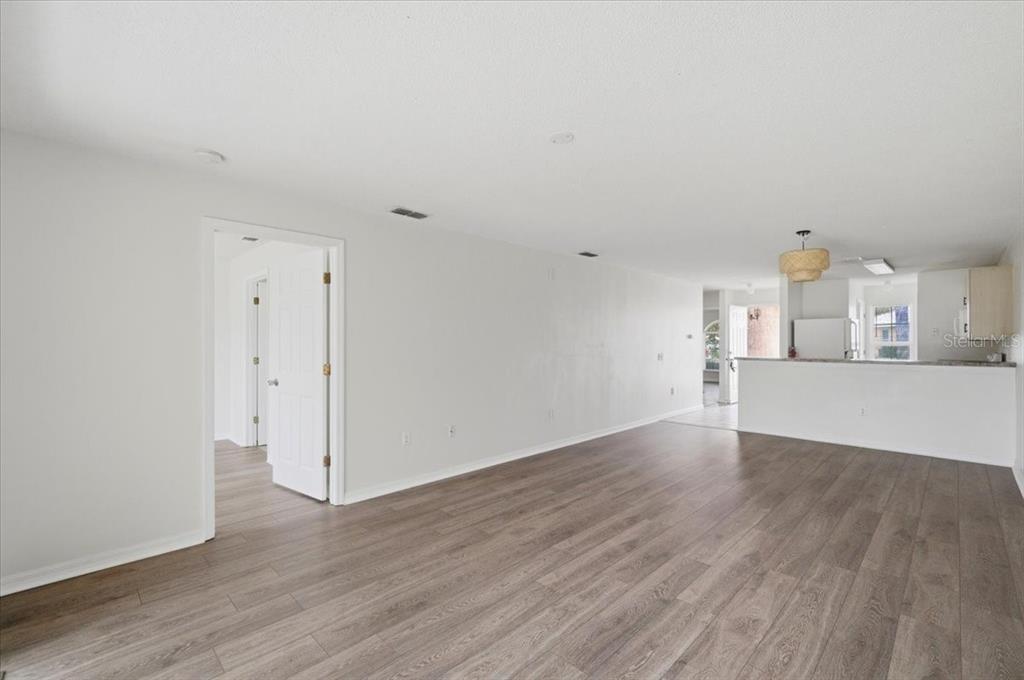 An open-concept living area features light gray walls, wood-look flooring, and a kitchen breakfast bar — 212 OCEAN BLUFF DRIVE, POINCIANA, FL