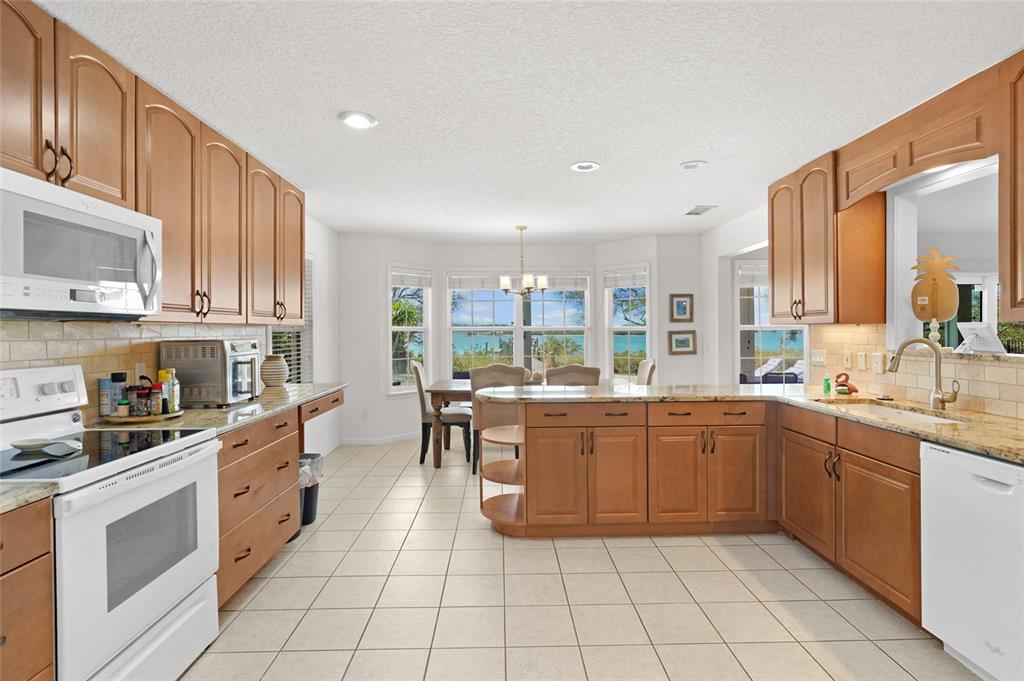 A kitchen with wood cabinets, granite countertops, and a dining area overlooking the water — 7101 MIDDLETON AVENUE, ST AUGUSTINE, FL