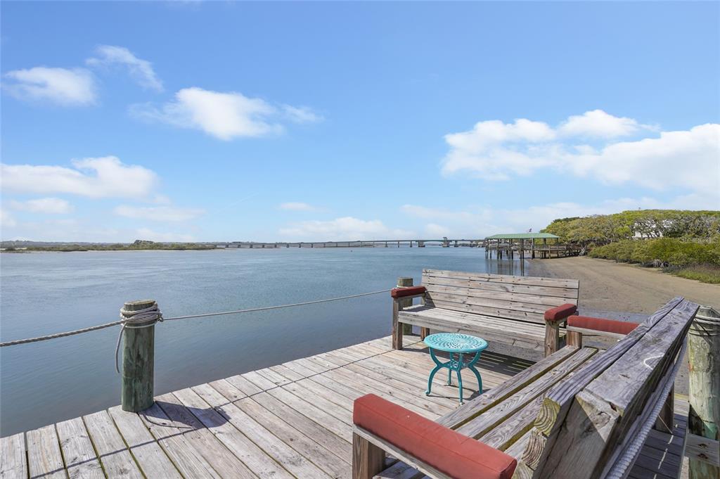 A wooden dock features two benches and a small table overlooking a wide river — 7101 MIDDLETON AVENUE, ST AUGUSTINE, FL