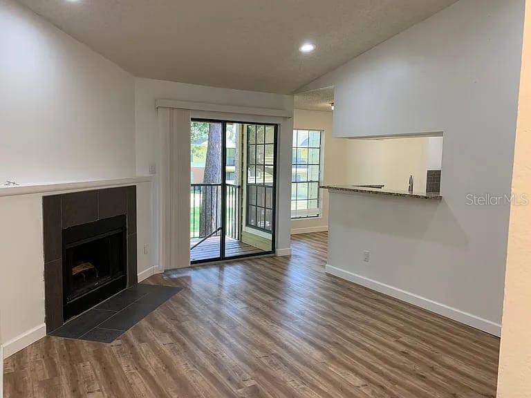 A living room features wood-look flooring, a fireplace, and a sliding glass door to a balcony — 8625 MALLARD RESERVE DRIVE UNIT 204, TAMPA, FL