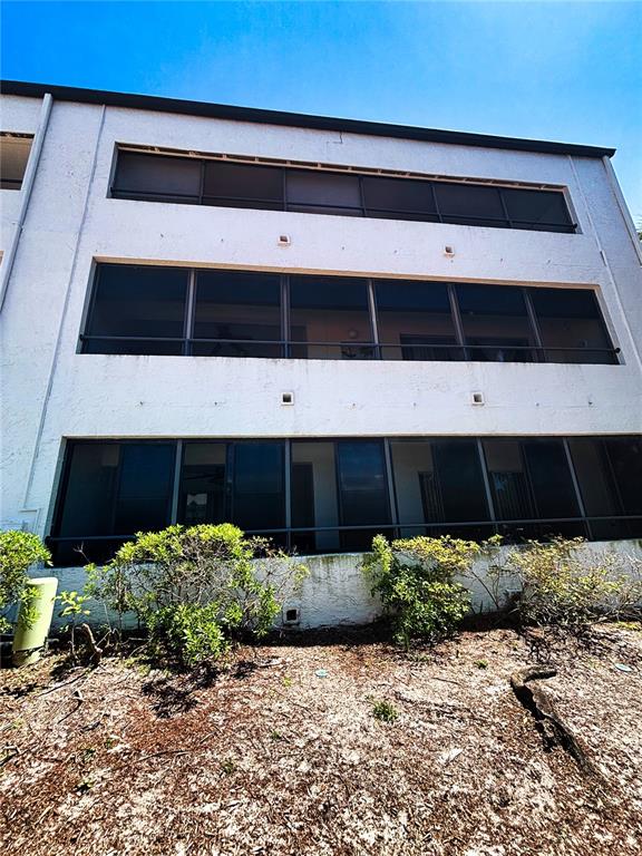 A three-story building exterior features screened-in balconies and a landscaped ground level — 2583 COUNTRYSIDE BOULEVARD UNIT 3309, CLEARWATER, FL