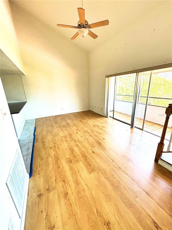 A living room with wood-look flooring, a vaulted ceiling, a ceiling fan, and sliding glass doors — 2583 COUNTRYSIDE BOULEVARD UNIT 3309, CLEARWATER, FL