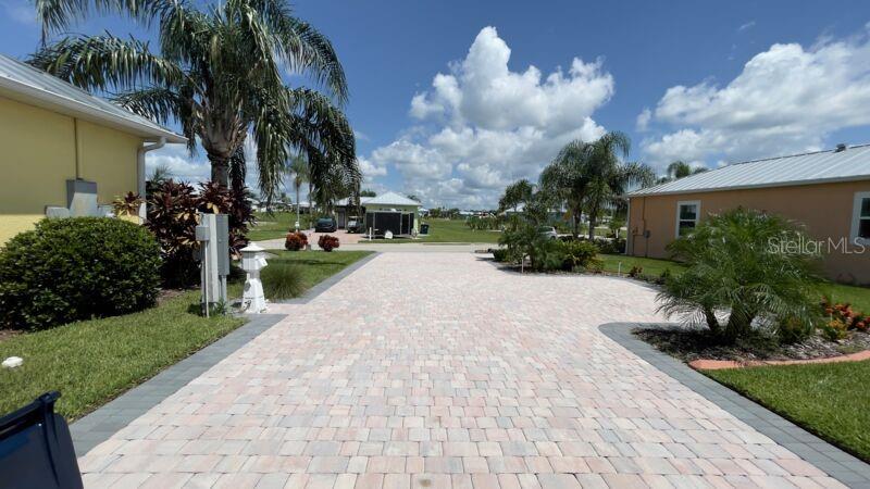 A paved driveway leads between two houses toward a distant building under a cloudy sky — 3015 WOOD DUCK DRIVE, POLK CITY, FL