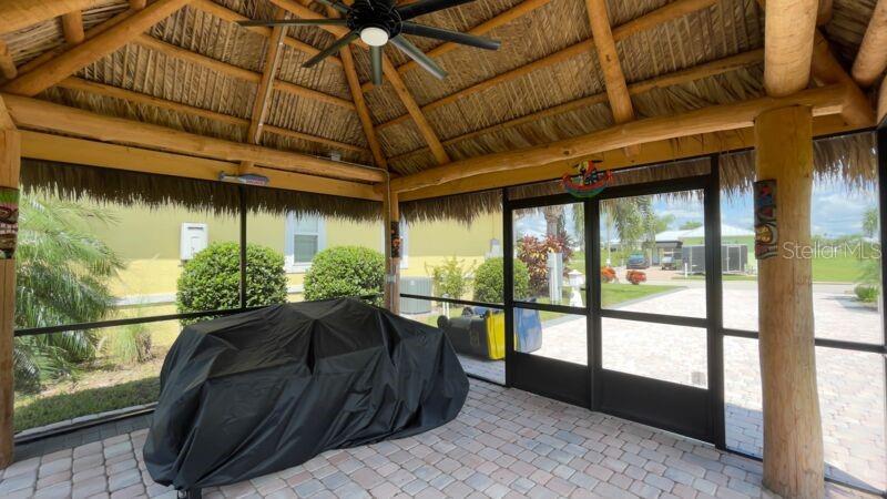 A screened-in tiki hut patio features a thatched roof, wooden beams, and a paved floor — 3015 WOOD DUCK DRIVE, POLK CITY, FL