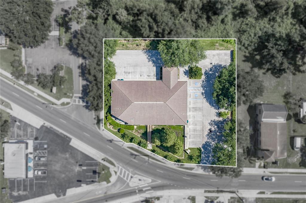 This aerial view shows a commercial building with a parking lot surrounded by trees — 1214 W REYNOLDS STREET UNIT 1, PLANT CITY, FL