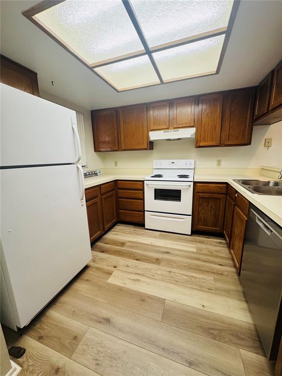 A kitchen features wood cabinets, white appliances, and light-colored wood-look flooring — 328 WOODLAKE WYNDE, OLDSMAR, FL