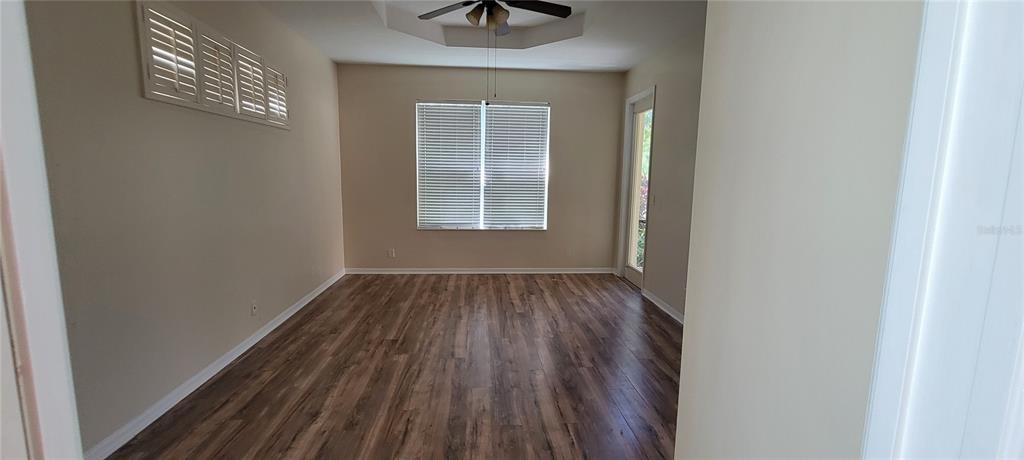 An empty room features wood-look flooring, a ceiling fan, and a window with blinds — 7217 ORCHID ISLAND PLACE, BRADENTON, FL
