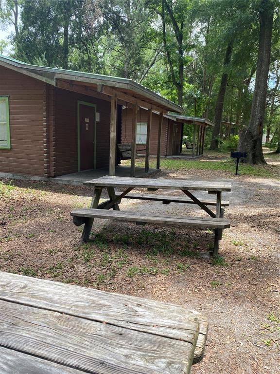 A wooden picnic table sits in front of a brown cabin with a porch — 8587 SW ELIM CHURCH ROAD, FORT WHITE, FL