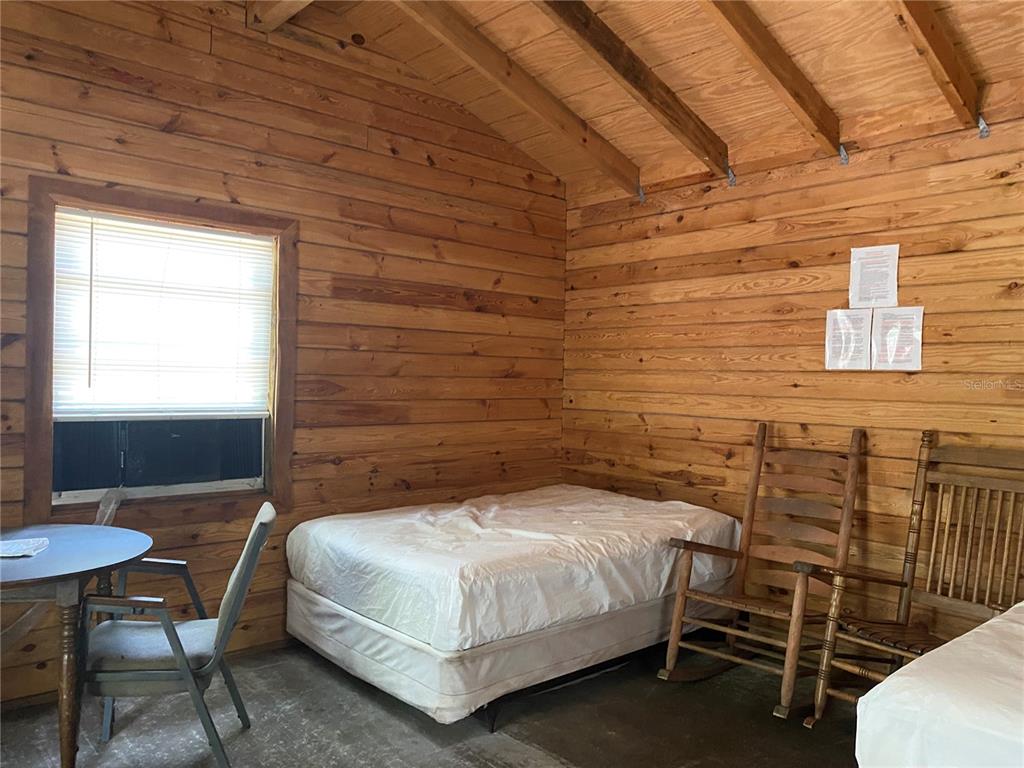 A rustic room features log walls, a bed, two rocking chairs, and a small table — 8587 SW ELIM CHURCH ROAD, FORT WHITE, FL
