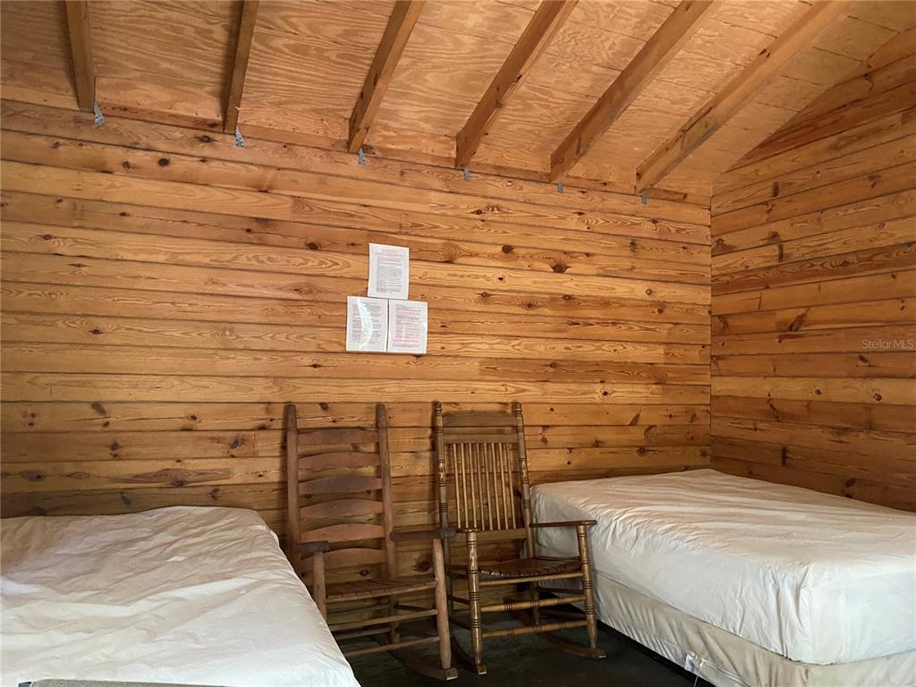 A rustic room with wood-paneled walls, two beds, and two wooden rocking chairs — 8587 SW ELIM CHURCH ROAD, FORT WHITE, FL