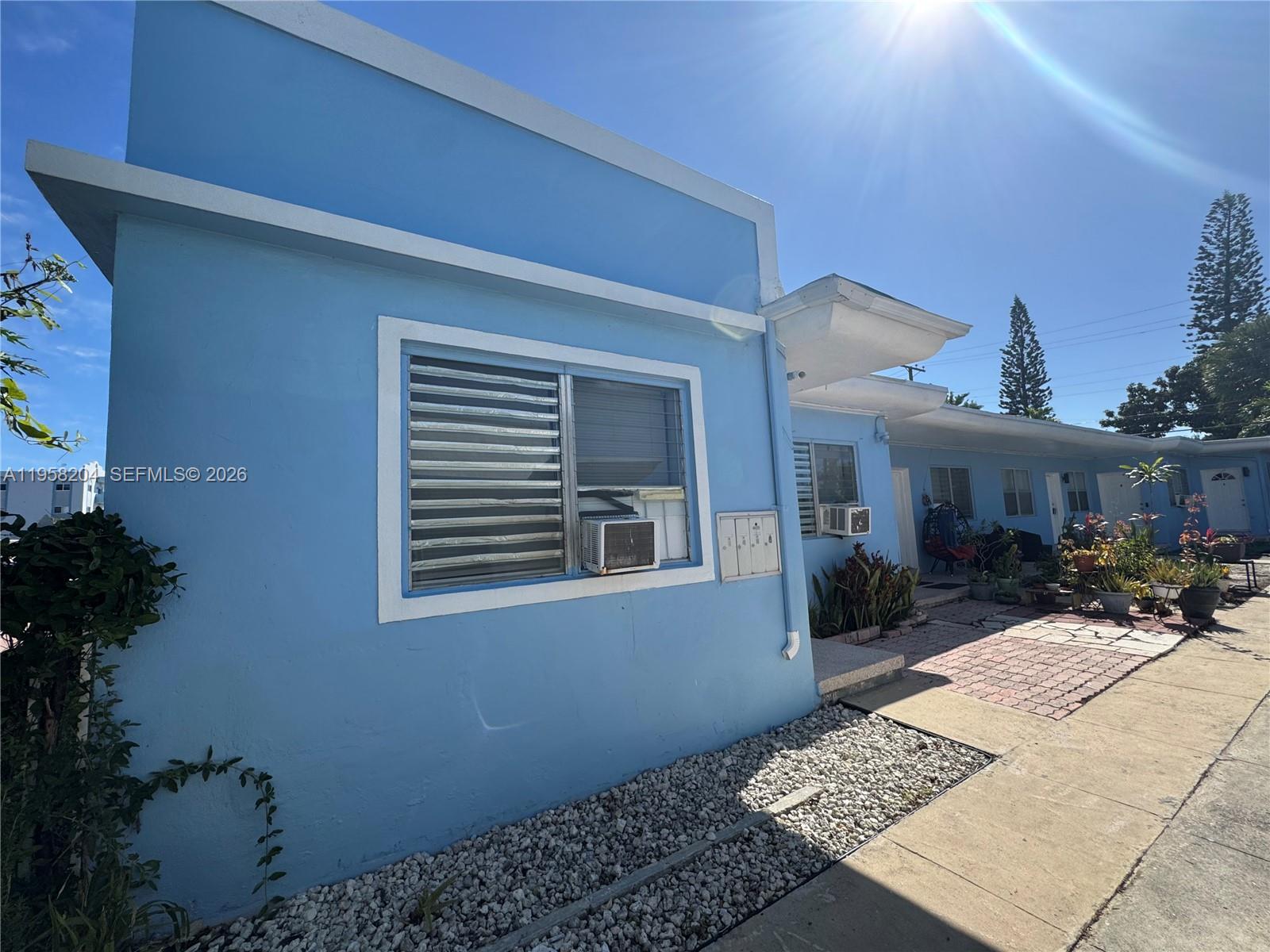 A blue exterior building features a window with a mounted air conditioning unit — 770 83rd St, Miami Beach FL 33141, MIAMI BEACH, FL
