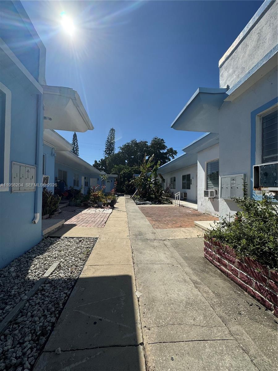 A narrow concrete walkway separates two rows of light blue single-story residential buildings — 770 83rd St, Miami Beach FL 33141, MIAMI BEACH, FL