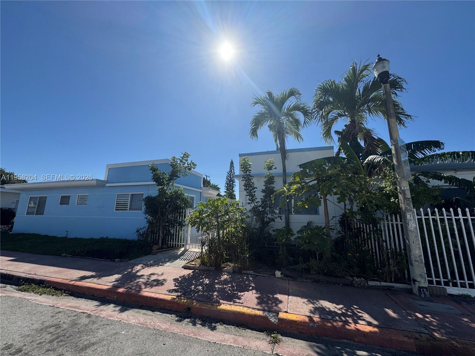 Two light blue houses stand behind a white fence under a bright sun — 770 83rd St, Miami Beach FL 33141, MIAMI BEACH, FL