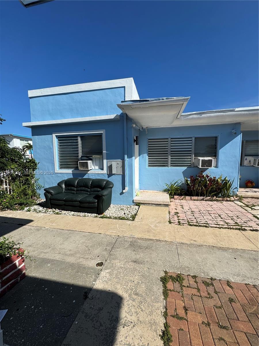A blue single-story building exterior features a green sofa placed on a gravel bed — 770 83rd St, Miami Beach FL 33141, MIAMI BEACH, FL