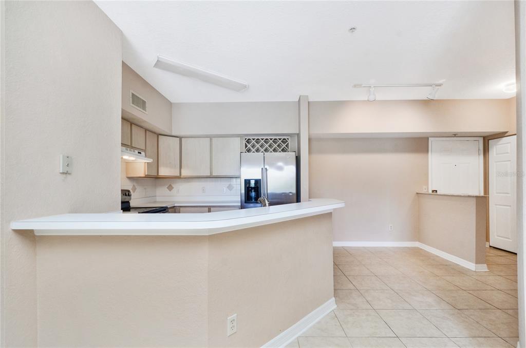 A kitchen with light-colored cabinets, stainless steel appliances, and a breakfast bar overlooking the room — 826 CAMARGO WAY UNIT 210, ALTAMONTE SPRINGS, FL