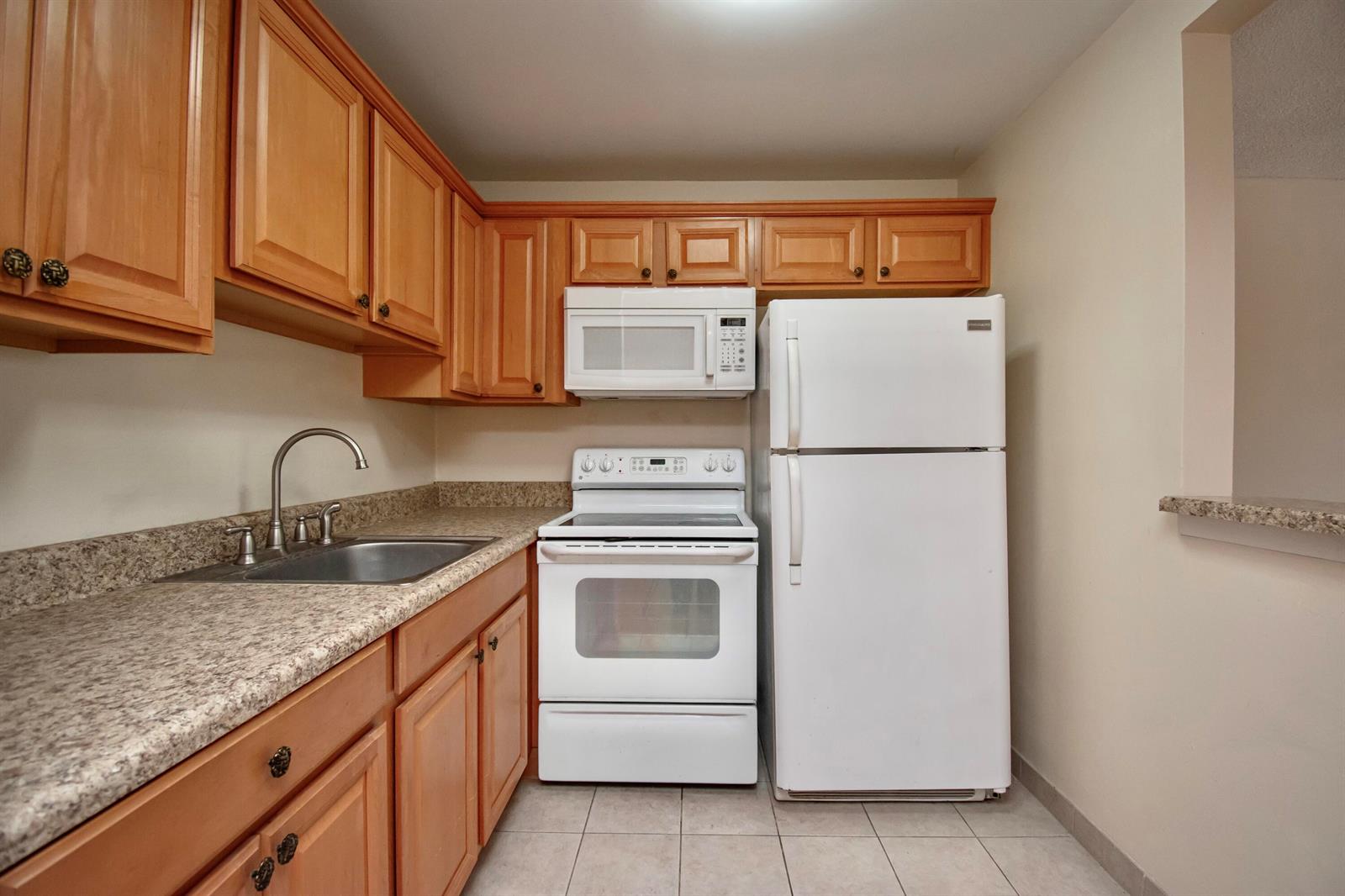 A kitchen with light wood cabinets, white appliances, and speckled laminate countertops — 197 Andover H, West Palm Beach FL 33417, WEST PALM BEACH, FL