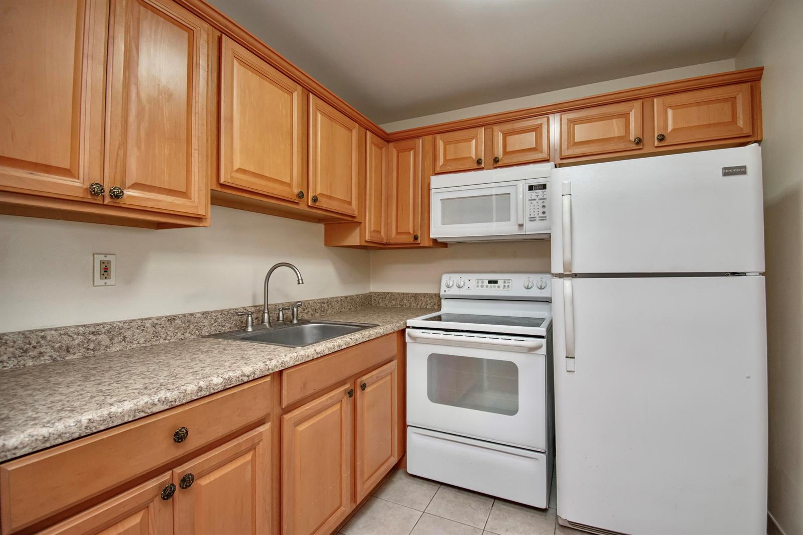A kitchen with light wood cabinets, white appliances, and speckled laminate countertops — 197 Andover H, West Palm Beach FL 33417, WEST PALM BEACH, FL