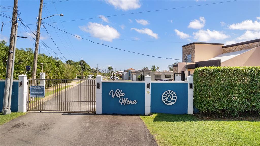 A gated entrance with a blue wall featuring the name Villa Mena and a logo — 682 SANTANA ROAD, ARECIBO, PR