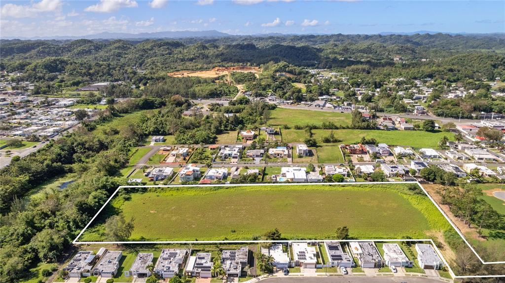 An aerial view shows a large, rectangular vacant lot surrounded by residential houses and trees — 682 SANTANA ROAD, ARECIBO, PR