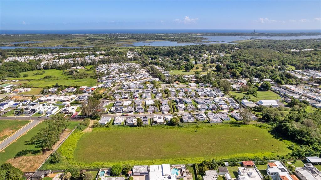 An aerial view shows a residential neighborhood with a large vacant lot in the foreground — 682 SANTANA ROAD, ARECIBO, PR