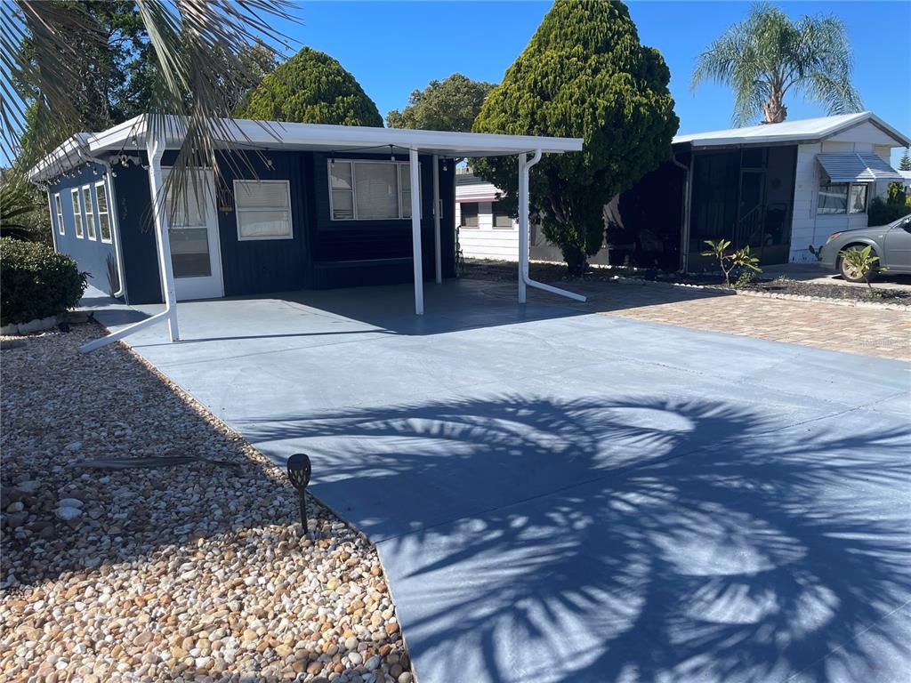 A dark blue mobile home features a covered carport and a paved driveway — 237 PALM CREST LANE, DAVENPORT, FL