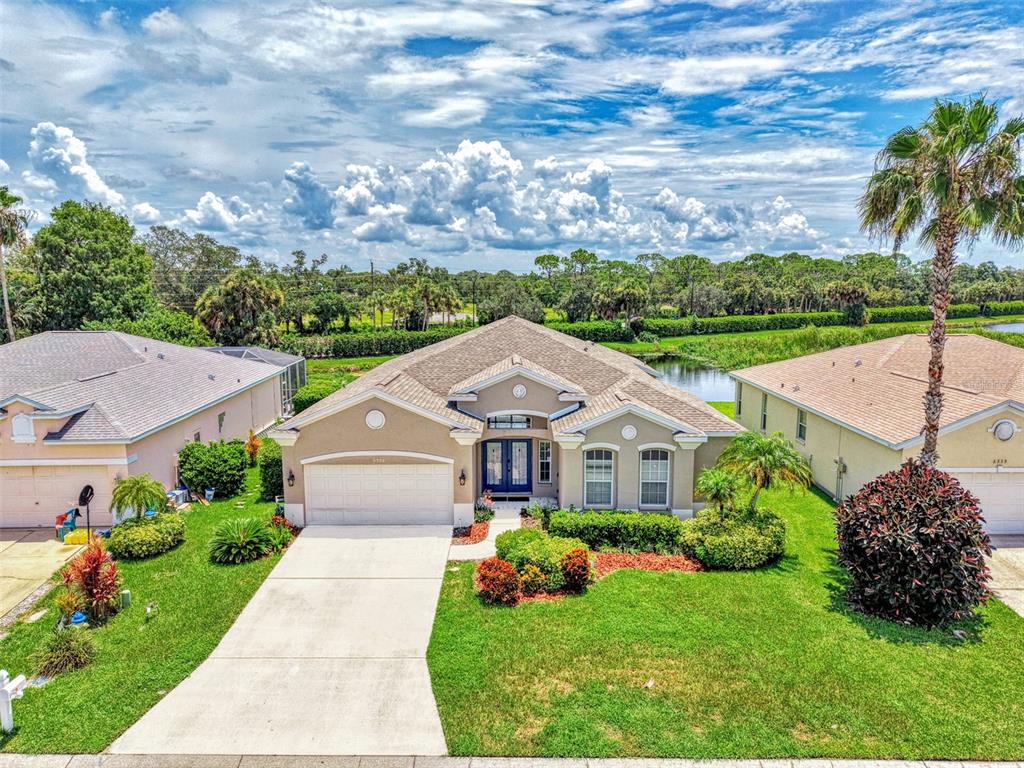 An aerial view of a single-story suburban house with a driveway, lawn, and pond — 6339 STURBRIDGE COURT, SARASOTA, FL