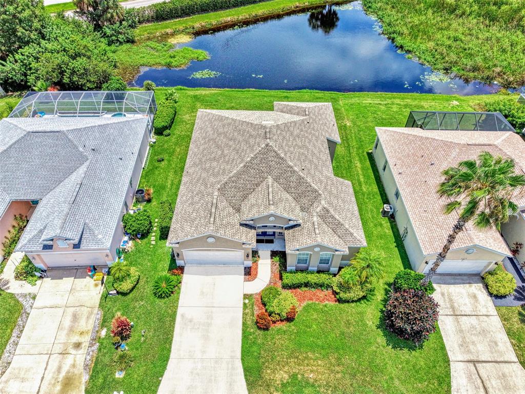 An aerial view shows three suburban houses with driveways, lawns, and a pond in back — 6339 STURBRIDGE COURT, SARASOTA, FL