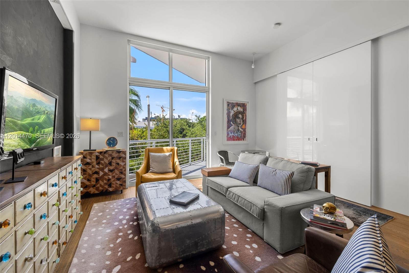 A living room features a metal coffee table, gray sofa, and balcony with outdoor views — 2001 Meridian Ave # 404, Miami Beach FL 33139, MIAMI BEACH, FL